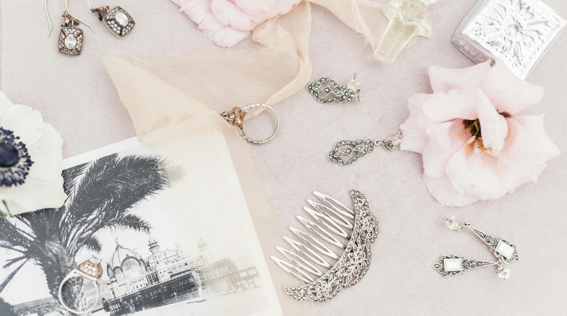 A delicate assortment of vintage jewelry and flowers in a flat lay composition.